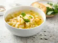 Pyszna zupa kalafiorowa przepis na rozgrzewający obiad. W misce kremowa zupa z kalafiorem, ziemniakami i marchewką, udekorowana natką pietruszki.