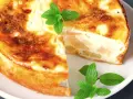 Pyszne ciasto z serka wiejskiego z kawałkami owoców, udekorowane listkami mięty.