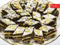 Pyszne ciastka z makiem, udekorowane lukrem i kandyzowaną skórką pomarańczową, ułożone na ozdobnej paterze.