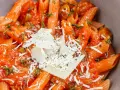 Pyszne dania z makaronem penne w sosie pomidorowym z parmezanem i ziołami. Idealne na szybki obiad.