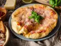 Langosz co to? Puszysty, złocisty placek z sosem pomidorowym i parmezanem, ozdobiony listkiem bazylii.
