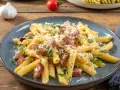 Penne rigate z boczkiem i parmezanem, posypane świeżą natką pietruszki. Pyszne spaghetti z serem, które zachwyca smakiem.