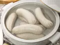 Biała kiełbasa w garnku, gotowa do przygotowania według przepisu.