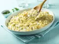 Kremowe makaronowe danie, idealne do przygotowania z przepisu na mac and cheese. Łyżka wydobywa porcję ciągnącego się sera.