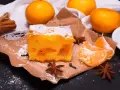 Puszyste ciasto z mandarynkami, posypane cukrem pudrem, obok świeże cząstki owoców i gwiazdki anyżu.