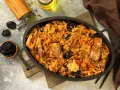 Pyszny bigos z kiszonej kapusty z kawałkami mięsa i śliwkami, podany w żeliwnym naczyniu.