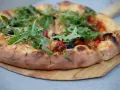 Pyszna pizza z rukolą i oliwkami na drewnianej desce. Proste ciasto na pizzę zawsze wychodzi, tworząc idealną bazę dla ulubionych dodatków.