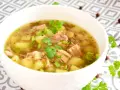 Aksamitny krupnik na rosole z kawałkami mięsa, ziemniaków i zielonej cebulki, udekorowany natką pietruszki.