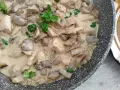 Pyszny kurczak z pieczarkami w sosie śmietanowym, udekorowany natką pietruszki, gotowy do podania.