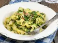 Pappardelle z boczkiem i szpinakiem, danie pełne smaku, podane na talerzu z widelcem.