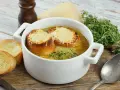 Aksamitna francuska zupa cebulowa z grzankami zapieczonymi pod serem i gałązką tymianku.