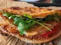 Pyszna tortilla z serka wiejskiego z rukolą i pomidorem, idealna na szybki lunch.