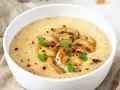 Aksamitny zupa krem z pieczarek, udekorowana plasterkami pieczarek, natką pietruszki i płatkami chili. Idealna na chłodne dni.