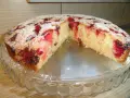 Wilgotne ciasto na oleju z owocami, posypane cukrem pudrem, prezentuje się apetycznie na szklanej paterze.