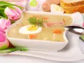 Biały barszcz z jajkiem, kiełbasą, marchewką i koprem, ozdobiony tulipanami i pisankami.