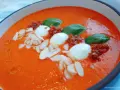 Aksamitny krem z pieczonej papryki z kulkami mozzarelli, suszonymi pomidorami, płatkami migdałów i listkami bazylii.