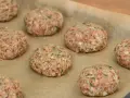 Surowe burgery z piekarnika, przygotowane z mielonego mięsa i kaszy, leżą na papierze do pieczenia.