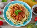 Pyszny, prosty sos do spaghetti z mielonym mięsem i pomidorami, udekorowany bazylią. Obok czosnek, pomidorki i kolorowy pieprz.