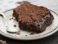 Pyszny murzynek na oleju, oblany gęstą czekoladą, czeka na talerzyku z łyżeczką.