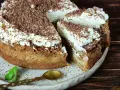 Pyszne ciasta z kremem, posypane wiórkami czekolady, czekają na spróbowanie. Obok leży złota łyżeczka i listek mięty.