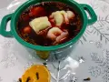 Aromaticzny barszcz z uszkami w zielonej miseczce, ozdobiony suszoną pomarańczą i goździkami.