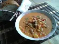 Pyszny bogracz z pieczarkami, ziemniakami i mięsem, posypany natką. Obok koszyk z chlebem.