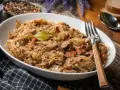 Pyszny bigos w białej misce, z widelcem. Zastanawiasz się, ile może stać bigos w lodówce? Nawet kilka dni, a smakuje coraz lepiej!
