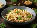 Penne ze szpinakiem i orzechami włoskimi w kremowym sosie, udekorowane natką pietruszki.