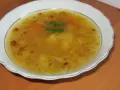 Prosta zupa cebulowa z ziemniakami, z kawałkami marchewki i natką pietruszki, podana w białej misce.
