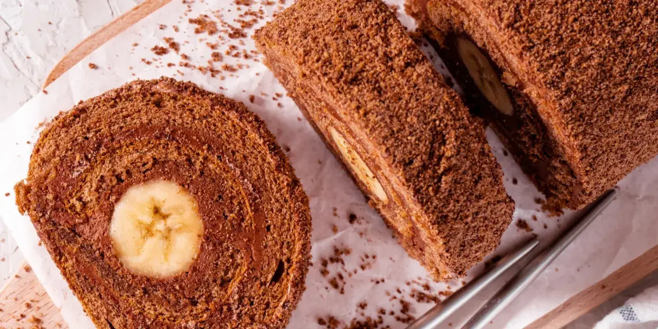 Czekoladowa rolada z bananem, posypana wiórkami, wygląda pysznie. Idealna na deser.