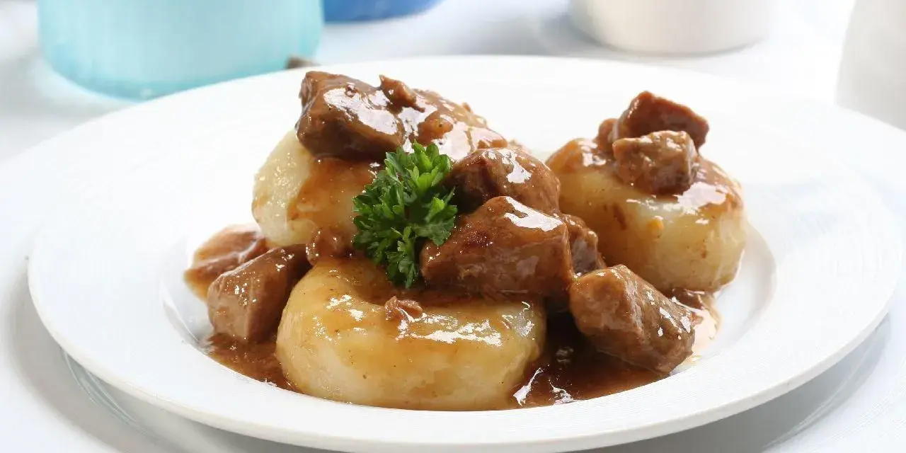 Kluski śląskie z gęstym, aromatycznym sosem mięsnym i gałązką natki pietruszki. Pyszny sos do kluski śląskie.