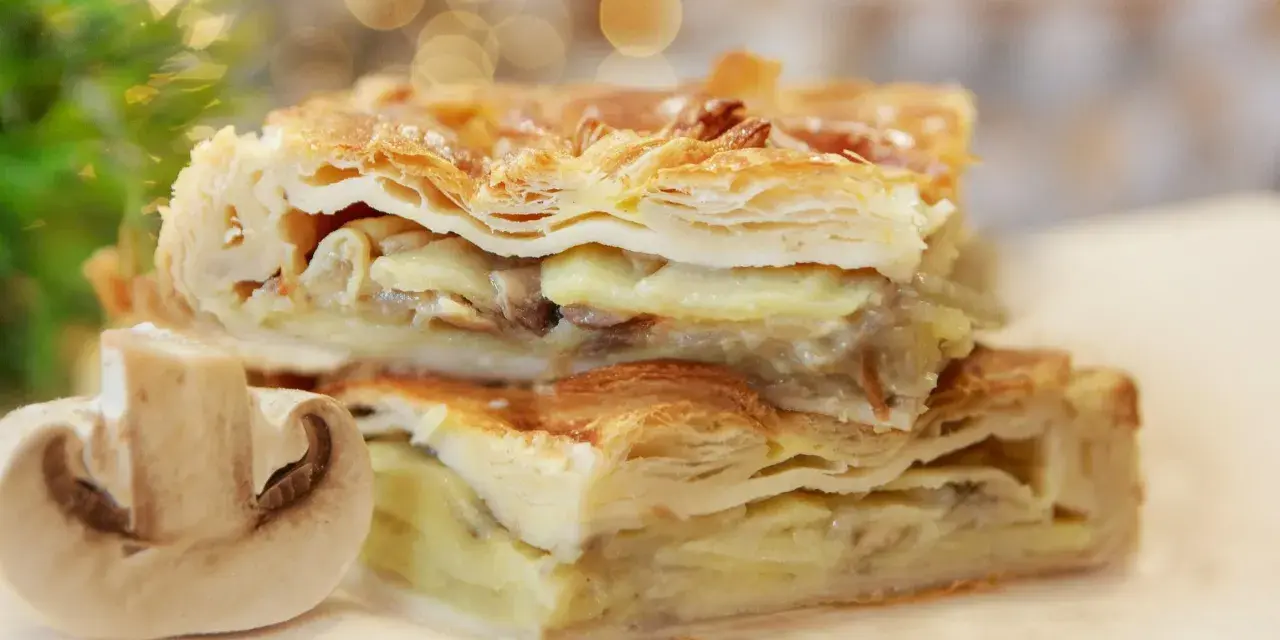 Chrupiące ciasto francuskie z kurczakiem i grzybami, podane z połówką pieczarki.