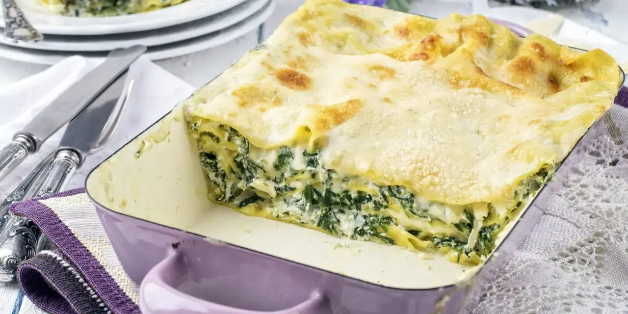 Pyszne lasagne ze szpinakiem i beszamelem, zapieczone na złoto, w fioletowym naczyniu. Idealna na rodzinny obiad.