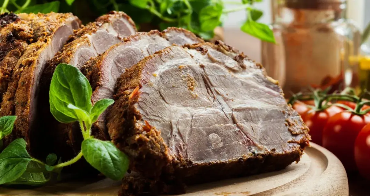 Soczysta karkówka w plastrach, pieczona z ziołami, podana z pomidorkami i świeżą bazylią.