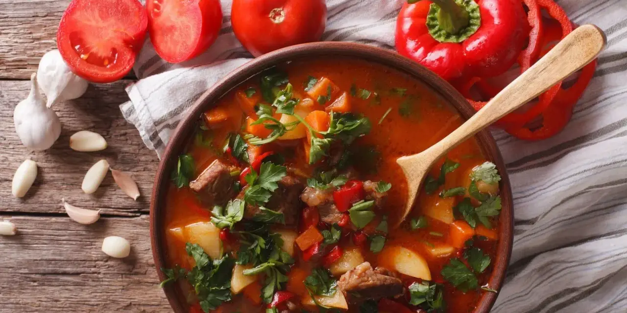 Aromaticzna zupa gulaszowa przepis. Mięso, ziemniaki, papryka i pomidory w bogatym bulionie, ozdobiona natką pietruszki.