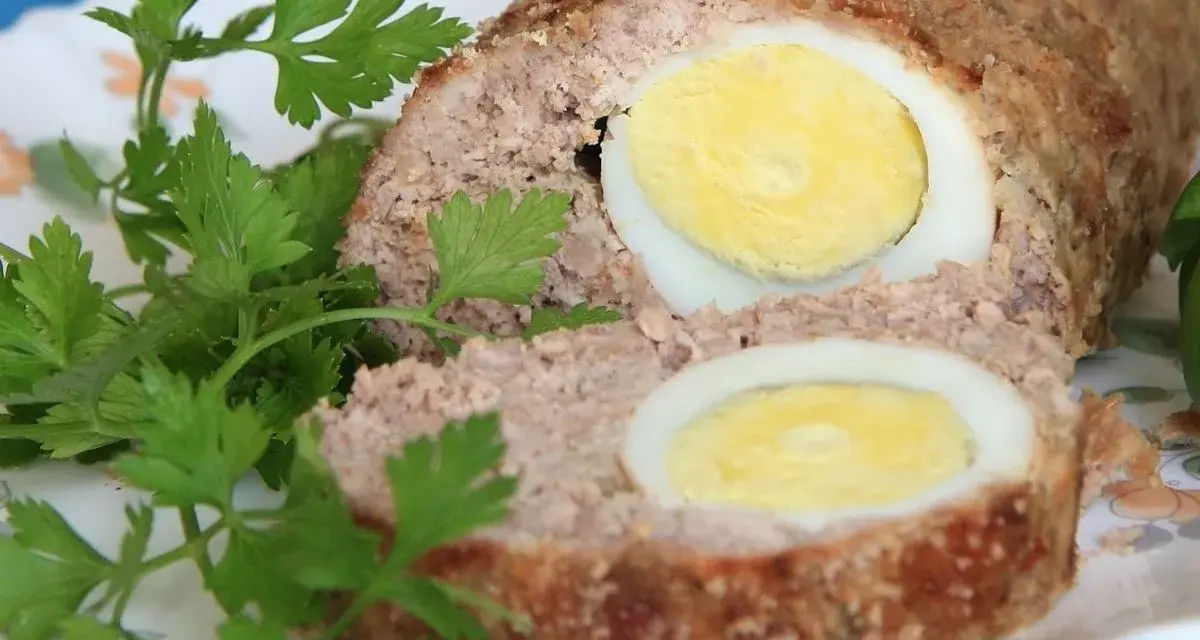 Pyszna pieczeń rzymska w sosie, z jajkiem w środku, udekorowana natką pietruszki.