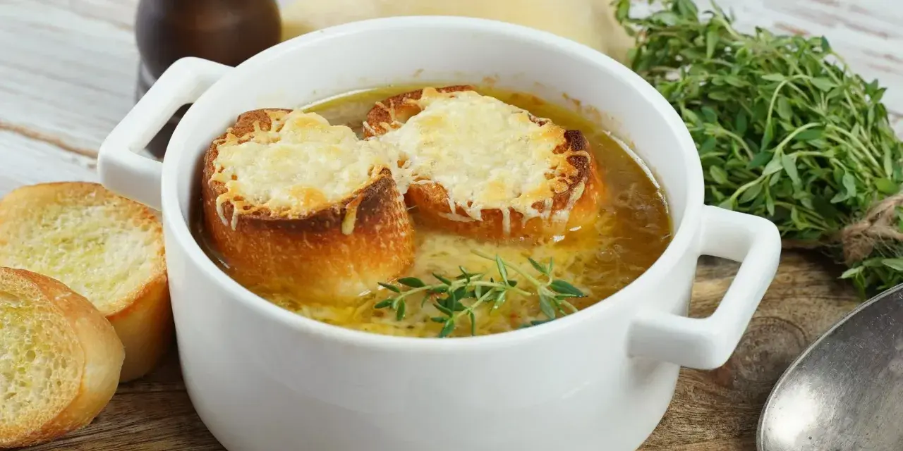 Aksamitna francuska zupa cebulowa z grzankami zapieczonymi pod serem i gałązką tymianku.