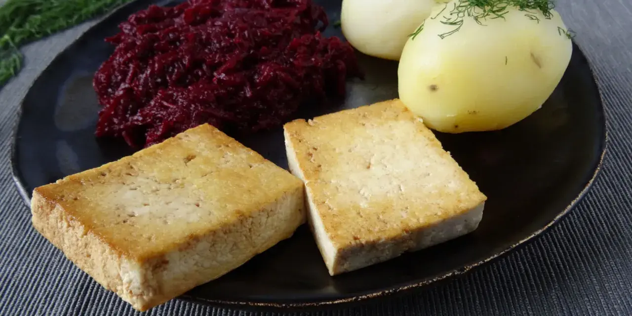 Złociste kotlety z tofu, ziemniaki z koperkiem i buraczki na talerzu.