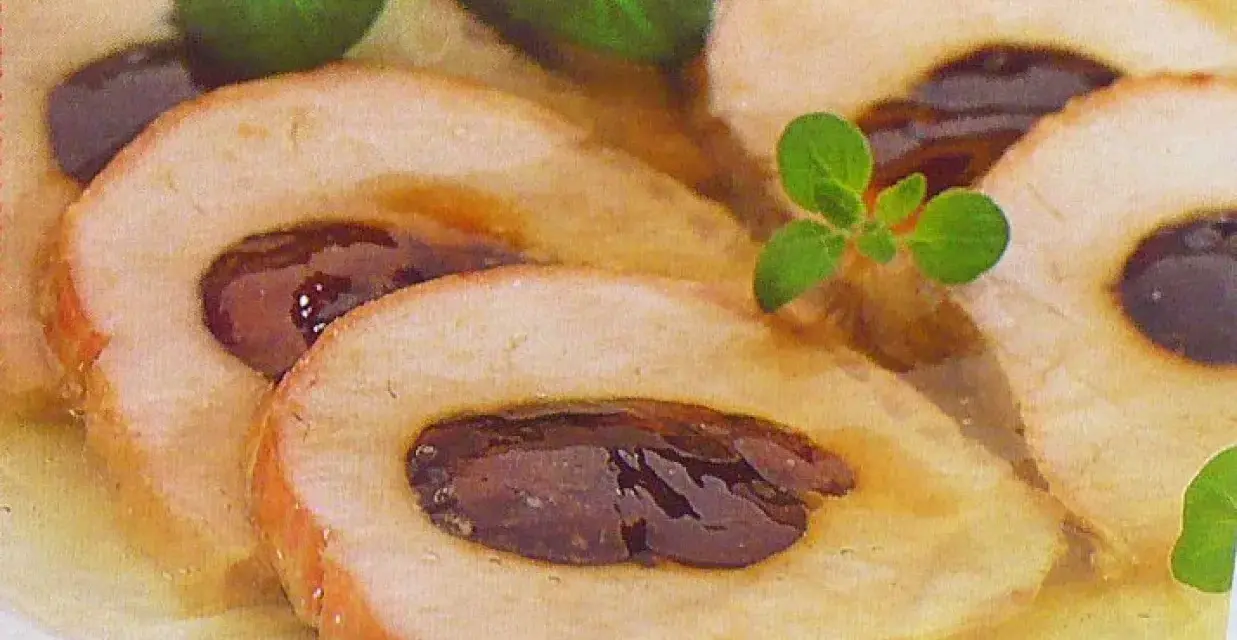 Schab ze śliwką w galarecie, elegancko pokrojony, z ziołami. Pyszne danie, które zachwyca smakiem i wyglądem.