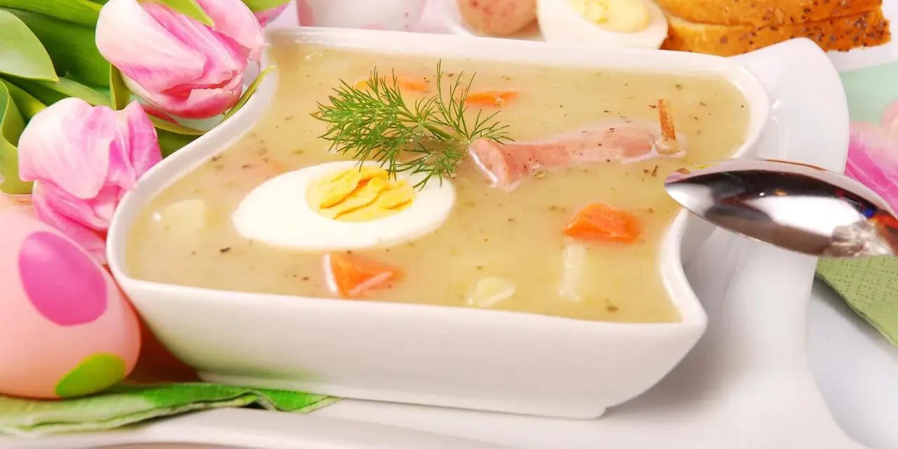 Biały barszcz z jajkiem, kiełbasą, marchewką i koprem, ozdobiony tulipanami i pisankami.