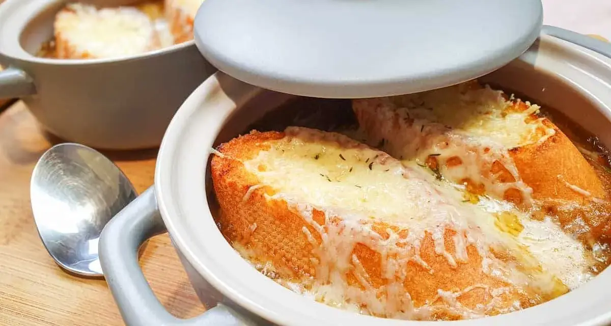 Gorąca zupa cebulowa z grzankami, zapieczona pod serem. Idealna na chłodne dni.