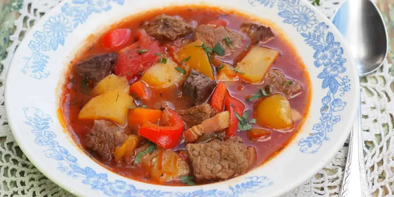 Aksamitna zupa gulaszowa przepis: sycące kawałki wołowiny, ziemniaki, papryka i marchewka w aromatycznym, pomidorowym sosie.