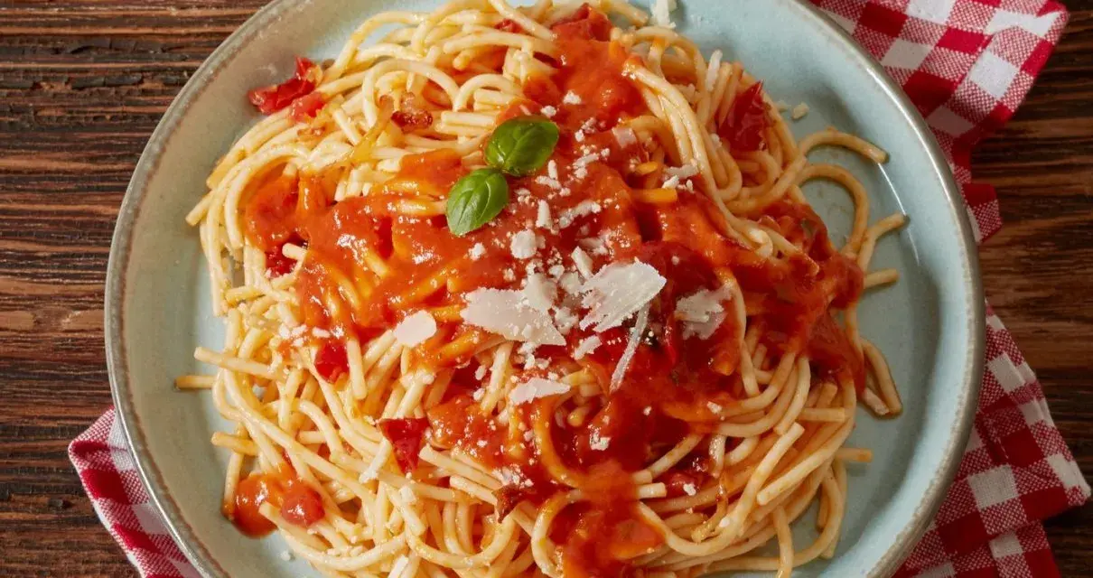 Pyszne spaghetti z sosem pomidorowym, parmezanem i listkiem bazylii. Idealne co do spaghetti na szybki obiad.