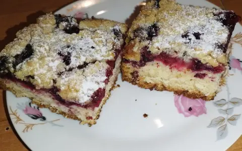 Pyszne ciasto drożdżowe z mrożonymi owocami, posypane cukrem pudrem. Idealne na deser!