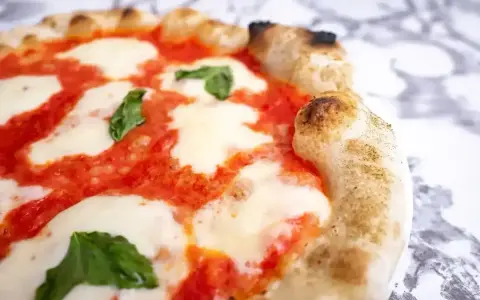 Puszyste ciasto na pizzę z sosem pomidorowym, ciągnącą się mozzarellą i listkami bazylii. Idealne na wieczór z przyjaciółmi.