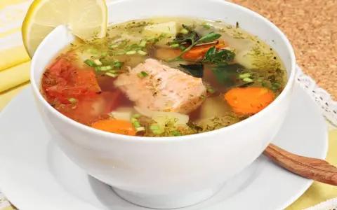 Aromatyczna zupa rybna przepis babci z łososiem, pomidorami, marchewką i ziemniakami, ozdobiona cytryną i natką.