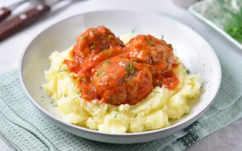 Pyszne pulpeciki w sosie pomidorowym na kremowym purée ziemniaczanym, posypane świeżym koperkiem.