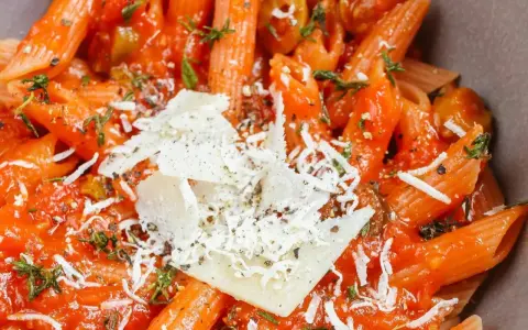 Pyszne dania z makaronem penne w sosie pomidorowym z parmezanem i ziołami. Idealne na szybki obiad.