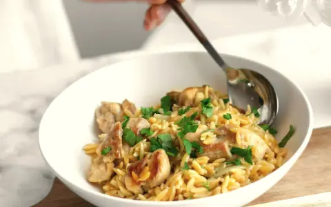 Miseczka pełna makaronu orzo z kawałkami kurczaka i posiekaną natką pietruszki. Idealny szybki sos do makaronu na obiad.