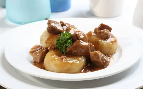Kluski śląskie z gęstym, aromatycznym sosem mięsnym i gałązką natki pietruszki. Pyszny sos do kluski śląskie.